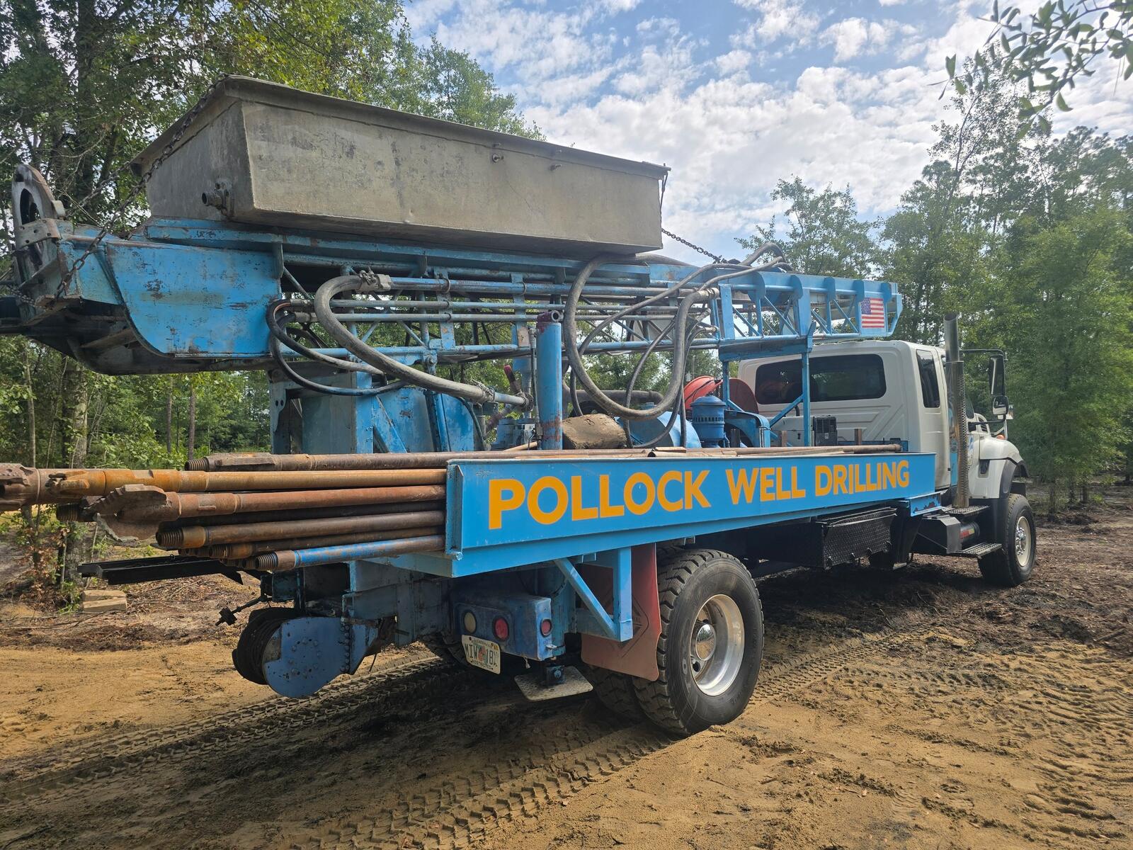 Pollock Well Drilling's blue drilling rig loaded with drill pipe on a job site in Bay County